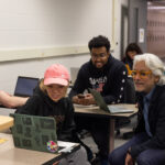 Photo of Professor Nagesh Shinde working with UW-Stout graphic design students. Within Professor Shinde’s Healthcare User Experience Design course, students are working with designers at Epic Systems, who serve as mentors for students as they create web, mobile app or kiosk products and services. / UW-Stout
