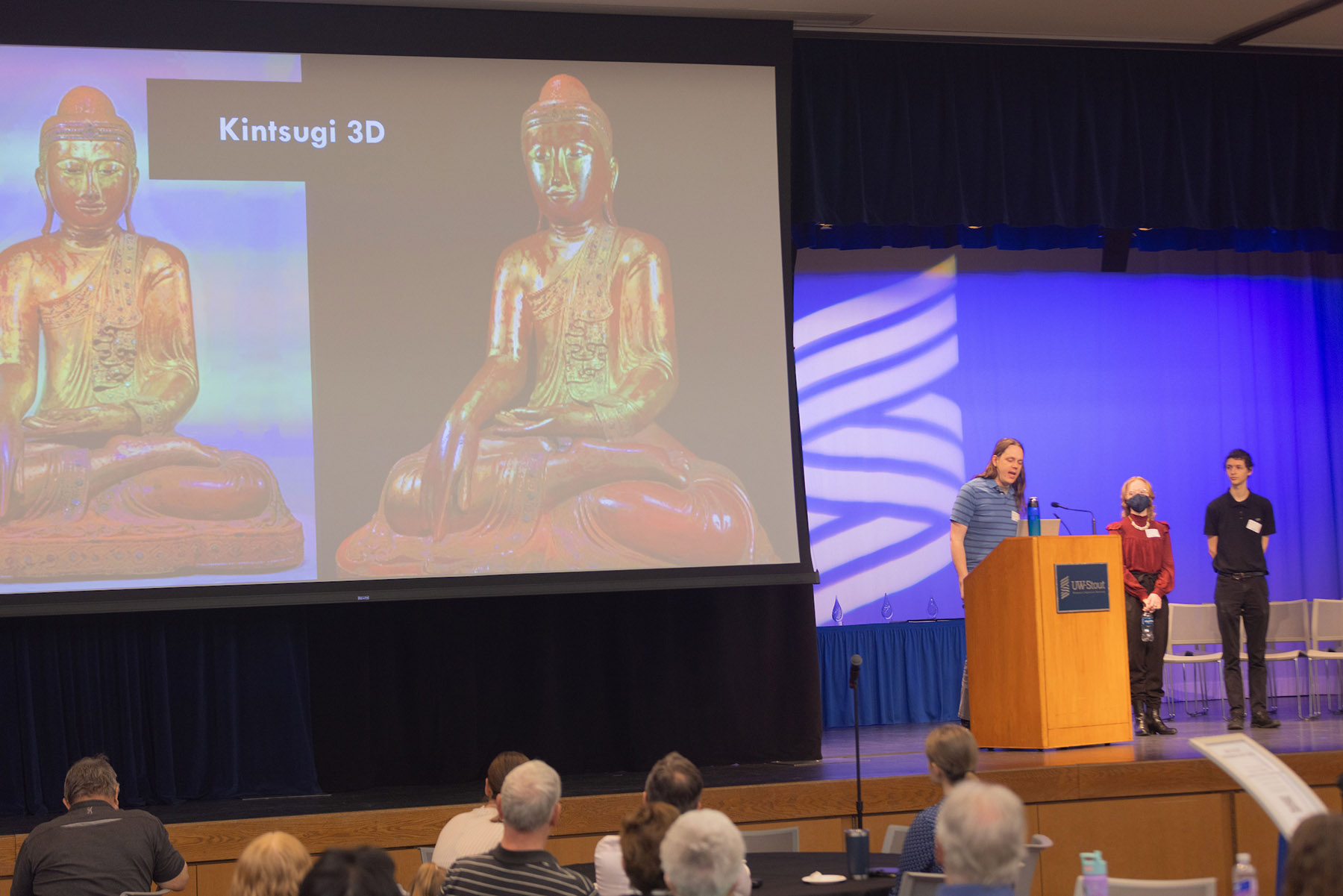 Photo of UW-Stout Assistant Professor Michael Tetzlaff, at podium, and students Chloe Ferguson and Luke Denney, giving a presentation about Kintsugi 3D at Research Day, May 6, 2025. / UW-Stout