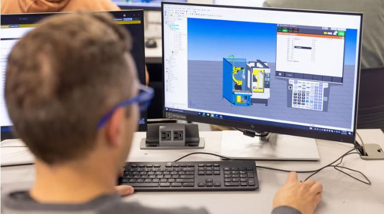 Photo of a UW-Stout manufacturing engineering student working on a program to control a machine in the university's robotics lab.