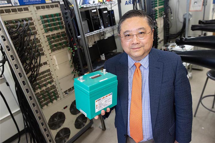 Photo of Deyang Qu, professor of mechanical engineering at UWM, holding a lithium iron phosphate battery, one of many needed to power electric vehicles. He has developed a strategy to recycle the retired batteries to create an economic opportunity. (UWM Photo/Troye Fox)