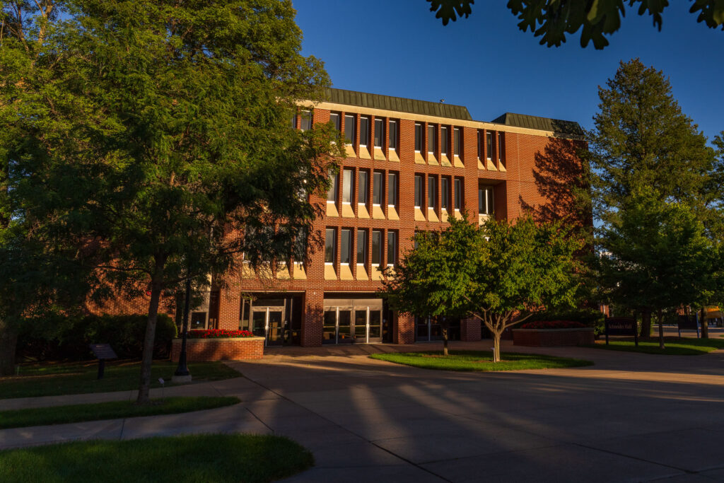Photo of UW-Eau Claire Schneider Hall in summer: Afternoon light falls on lower campus, including the Schneider Hall exterior in this summer scene.
