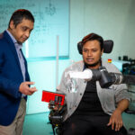 Photo: Habib Rahman (left), director of UWM's Biorobotics Lab, and PhD student Md Mahafuzur Rahaman Khan demonstrate their lab's assistive robotic arm that could be mounted to wheelchairs to help stroke and spinal cord injury patients perform everyday tasks. (UWM Photo/Troye Fox)