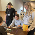 Photo: Nursing students Justin Gmach, Anika Roush and Aggie Rieder role-play as they “sell” jewelry” at a mock pawn shop as part of a poverty simulation activity for all UWO traditional senior nursing students.