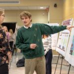 Photo of junior Finn Patenaude, a geography major with GIS concentration, presenting maps on optimal sites for wildlife crossings and the mass migration of monarch butterflies during UWL’s Geography & Environmental Science Department reverse career fair where students shared their projects with employers.