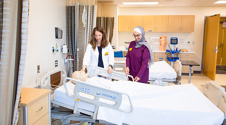 Photo of Melissa Melcher (left), clinical assistant professor, and Bayan Alqam, teaching assistant and PhD nursing student, check a manikin in the Clinical Skills Lab at the new UWM James and Yvonne Ziemer Clinical Simulation Center. (UWM Photo/Elora Hennessey)
