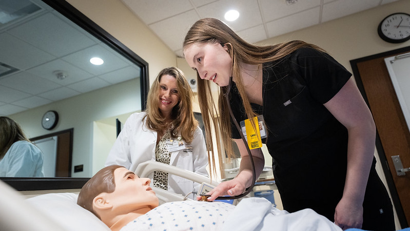 Photo: Sienna Isaacson, the first graduate of the 3+1 nursing pathway linking the University of Wisconsin–Platteville and UW-Oshkosh, practices assessing lung sounds on a simulation mannequin in the School of Nursing and Health Professions lab at UWO. Sarah O’Connell, co-director of the Accelerated Nursing program at UW-Oshkosh, observes during the clinical skills exercise.