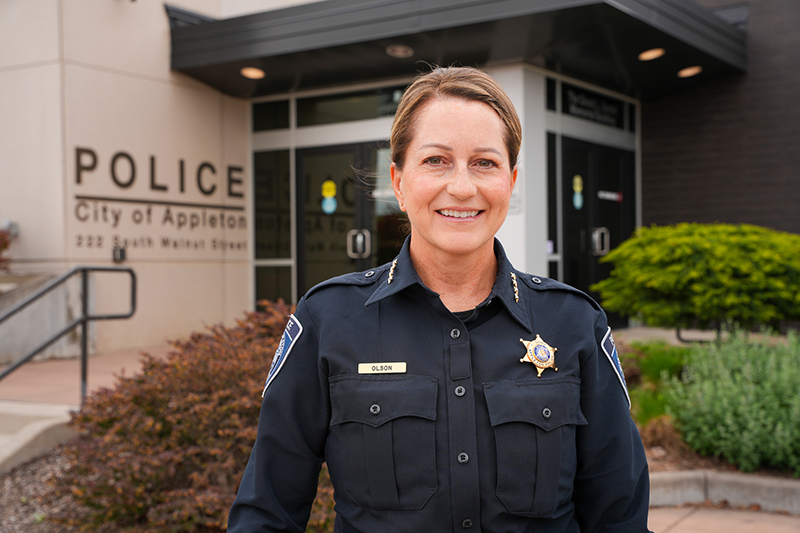 Photo: Polly (Reinke) Olson stands outside the Appleton Police Department headquarters in Appleton. The 1995 University of Wisconsin–Oshkosh biology graduate became the department’s first female police chief in 2023 and will retire in January 2027 after 26 years of service.