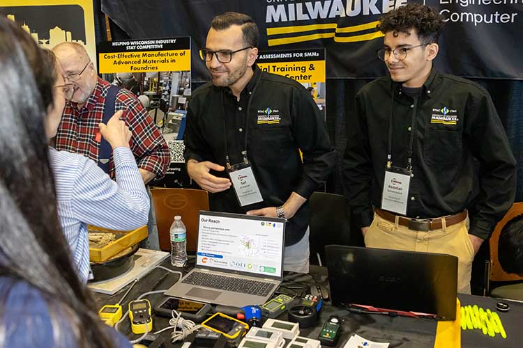 Photo: UWM researchers Saif Al Hamad (center) and Abdallah Benelmadjat (right), who both work in the lab of UWM Professor Ryo Amano, explain what an energy audit entails at their booth in the Innovation Showcase at the Wisconsin Drives Manufacturing Summit. (Wisconsin Drives Manufacturing photo)