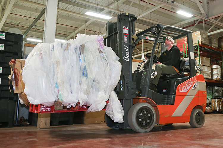 Photo: Ben Konitzer, recycling and solid waste specialist at UWM, uses a forklift to move a bale of compacted plastic film, a product of UWM’s newest recycling program. (UWM Photo/Elena Leshok)