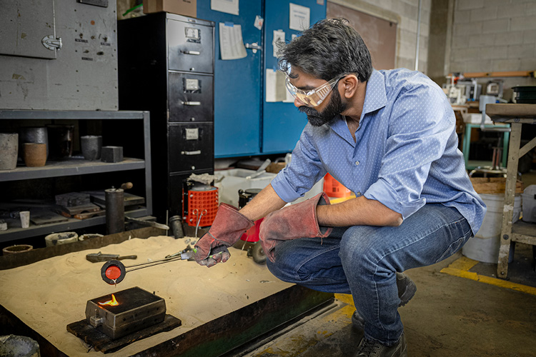 Photo: Swaroop Behera, a doctoral student in engineering, pours molten tin into a mold, a process known as metal casting. (UWM Photo/Andy Manis)