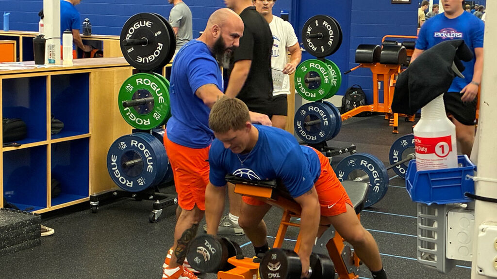Photo: Former Chicago Blackhawks trainer Paul Goodman (standing, left) coaches a UW-Platteville football player through chest-supported rows during a workout at the Pioneer Activity Center on Sept. 9, 2026. Goodman took over as football strength and conditioning coach in August 2026.