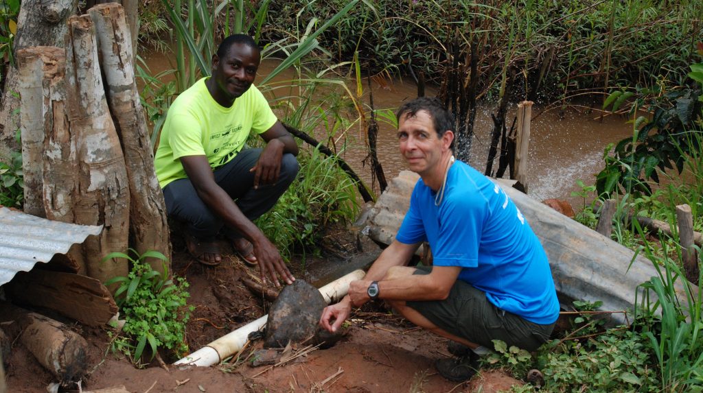 UW-Stout Professor Tom Lacksonen and Hastings Mkwandwire, a resident of Mzuzu, Malawi, observe one of Mkwandwire’s hand-built hydroelectric generators under a metal covering.