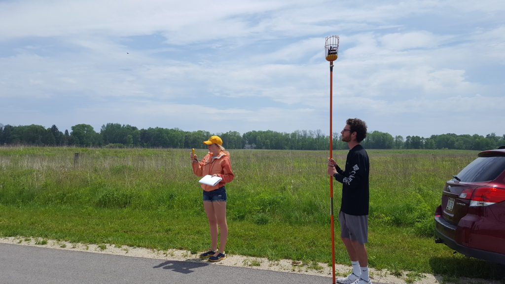 UW-Eau Claire students Molly McIlquham and Kyle Geib use an ozone monitor to measure the air at the same height at every stop during their fieldwork along Lake Michigan. They also record the local conditions, like temperature and wind speed, as measured by a hand-held weather meter.