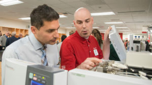 Photo of Carmine Savaglio, SC Johnson senior research scientist and UW-Parkside graduate, reviewing Shimadzu instrumentation with Shimadzu Field Service Engineer David Hobbs