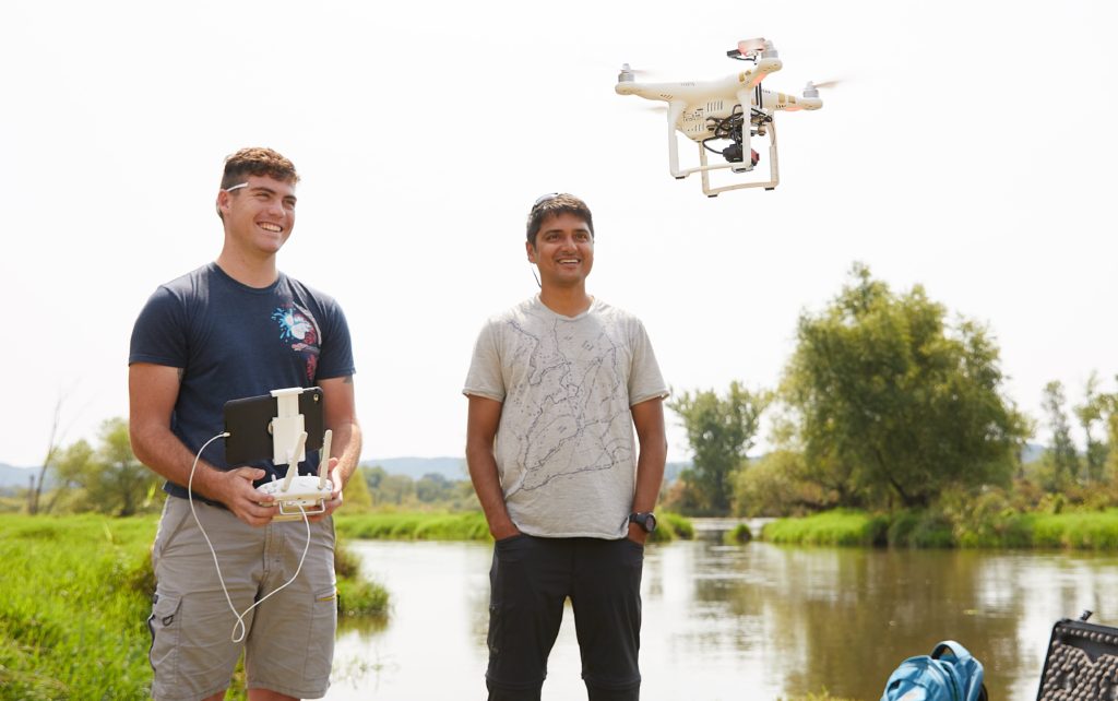 Photo of UW-La Crosse student Zachary Woodcock, left, who earned a summer research grant to use drones to conduct aerial surveys of purple loosestrife, an aquatic invasive plant with help from UWL faculty mentor and remote sensing scientist, Niti Mishra, right. Here Woodcock takes a drone survey test flight at the La Crosse River Delta near Bangor, Wisconsin.