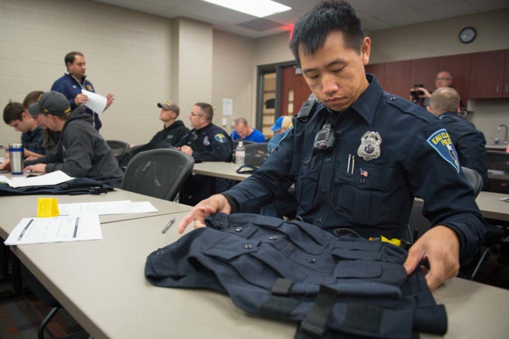Photo of Mark Vang, an officer with the Eau Claire Police Department, who is looking at a vest he will wear as part of a research project with UW-Eau Claire kinesiology students and faculty to determine if the vests will help ease back pain among police officers.
