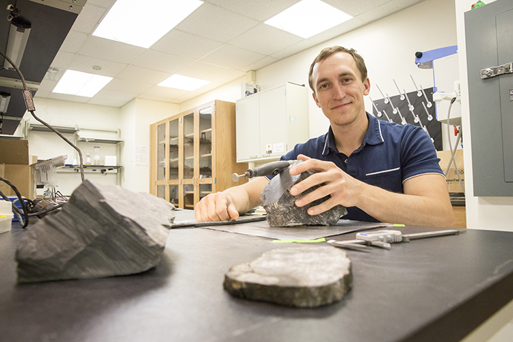 Photo of Erik Gulbranson, paleoecologist and visiting assistant professor at UWM, studying some of the fossilized trees he brought back from Antarctica. Gulbranson is returning there for further research this year. (UWM Photo/Troye Fox)