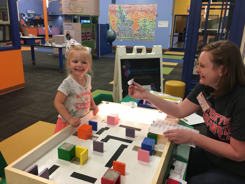 Photo of Clara Wojkiewicz (left) participating in an activity at the Children's Museum of Fond du Lac while UW-Fond du Lac student Grace Hudson monitors her progress.