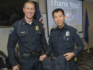 Photo of Matt Rokus, deputy chief of police, (left) issueing Eau Claire police officer Mark Vang his load-bearing vest.