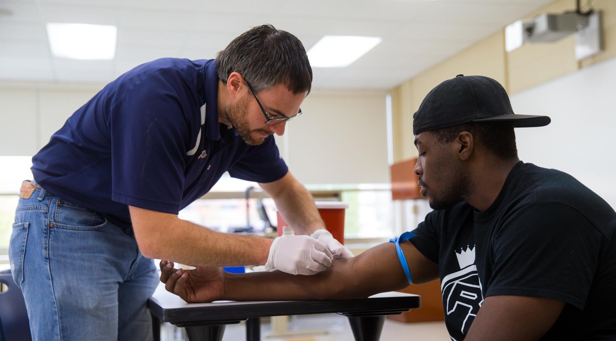 Dr. Matthew Rogatzki draws the blood from the football player prior to a JV game for analysis of biomarkers.