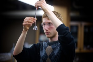 male student with lab goggles analyzes contents of a beaker