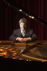 Zach Halmstad beside an open piano