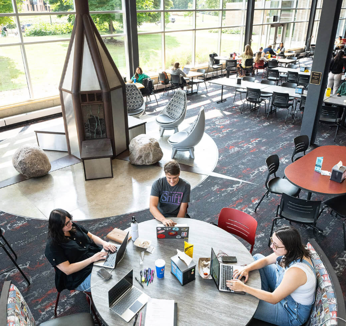 Three college students studying while seated at a table in the student center.
