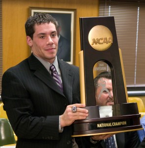 A UW-Whitewater football player displays the team's national championship trophy