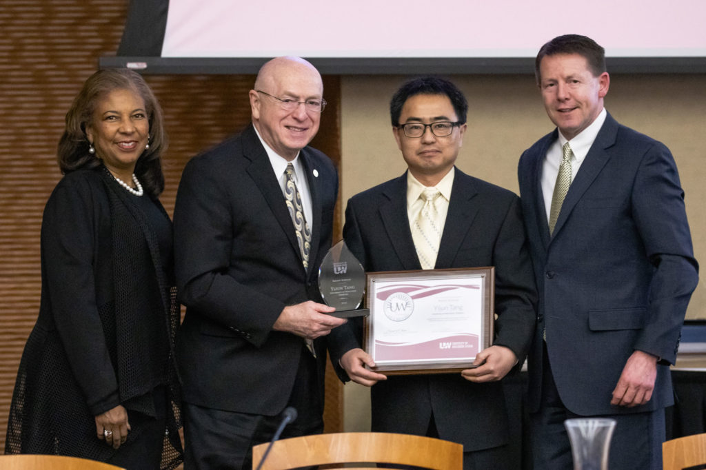 Photo of 2019 Regent Scholar Yijun Tang, holding plaque, with (from left) Regent Eve Hall, President Ray Cross, and Regent President John Robert Behling. (Photo by Craig Wild/UW-Madison)