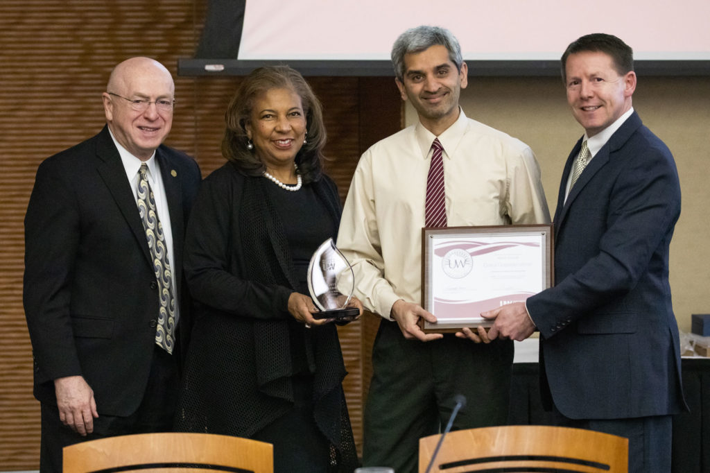 Photo of 2019 Regent Scholar Gokul Gopalakrishman, holding plaque, with (from left) President Ray Cross, Regent Eve Hall, and Regent President John Robert Behling. (Photo by Craig Wild/UW-Madison)