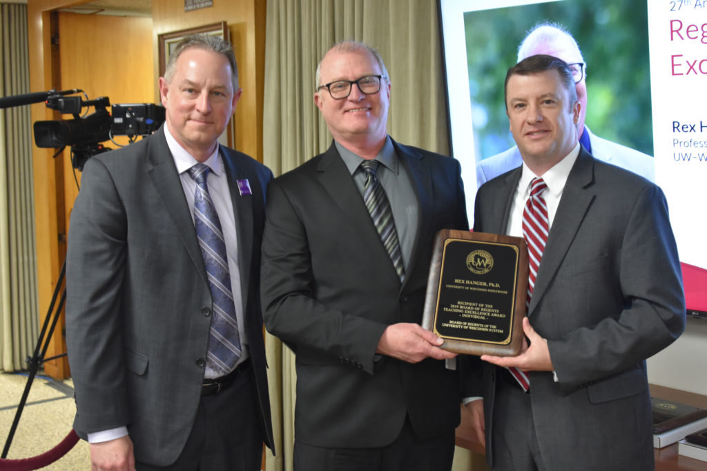 Photo of Professor Rex Hanger (center) from UW-Whitewater receiving a UW System Board of Regents 2019 Teaching Excellence Award at the Board of Regents meeting held in Madison on April 5, 2019. Also pictured (left) UW-Whitewater Vice Provost Greg Cook and Regent Jason Plante (right).