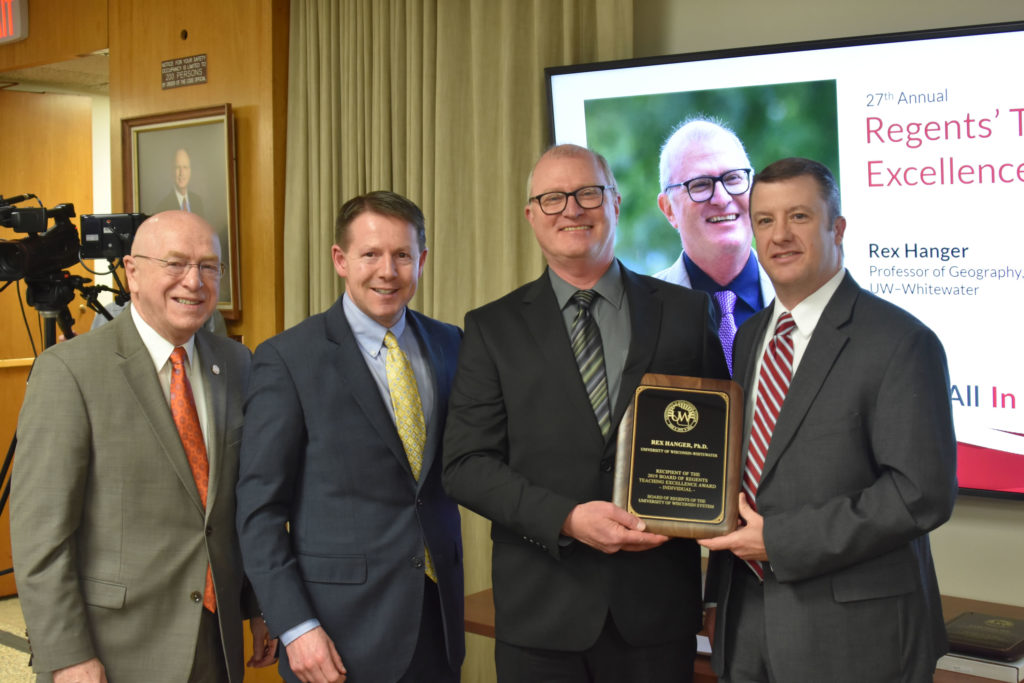 Photo of UW-Whitewater Professor Rex Hanger (second from right) receiving a UW System Board of Regents 2019 Teaching Excellence Award at the UW System Board of Regents meeting held in Madison on April 5, 2019. Also pictured (from left:) UW System President Ray Cross, Regent President John Robert Behling, and Regent Jason Plante.