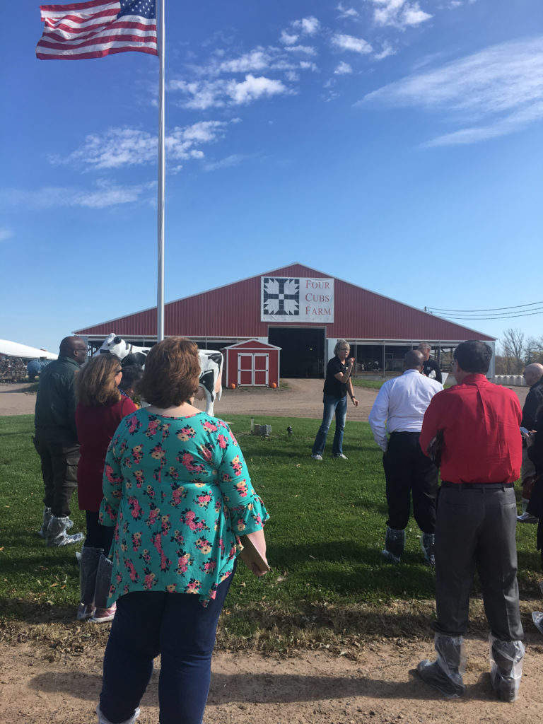 Photo of Regent Cris Peterson welcoming University of Wisconsin System officials, UW Regents, guests, and the media to a tour of her family dairy farm, Four Cubs Farm.