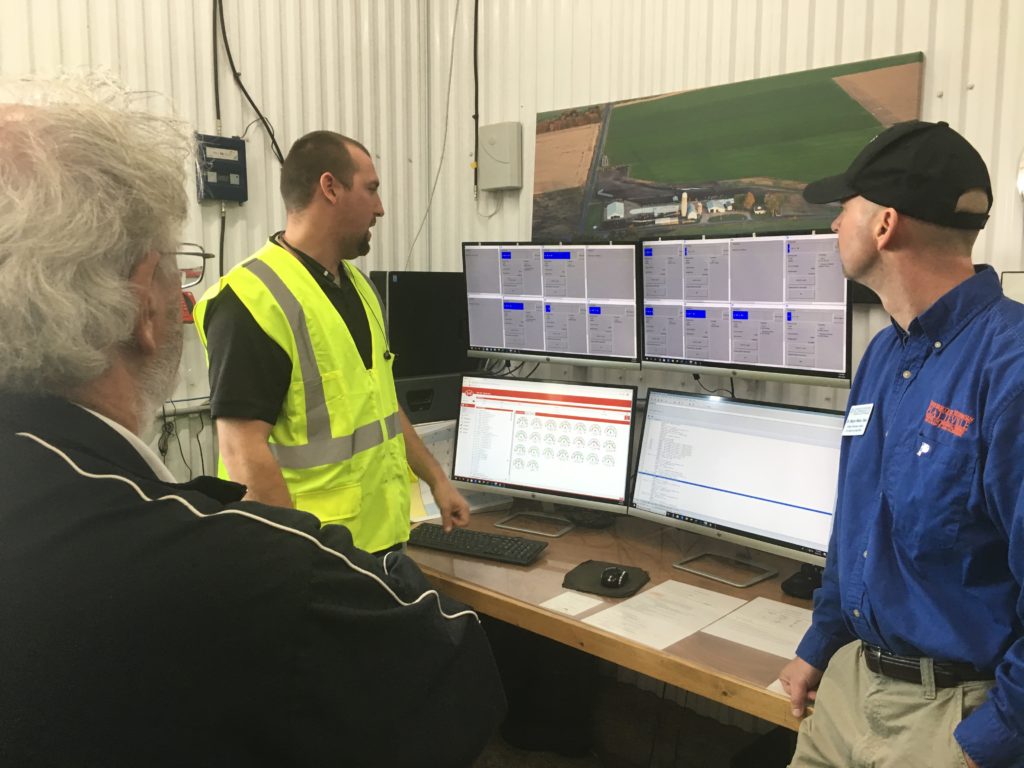 Photo of Dale Gallenberg, Dean of the College of Agriculture, Food and Environmental Sciences at UW-River Falls (left), and Wayne Weber, Dean of the College of Business, Industry, Life Science and Agriculture at UW-Platteville (right), observing computer monitoring of dairy cows at Four Cubs Farm in Grantsburg run by UW Regent Cris Peterson and her family.