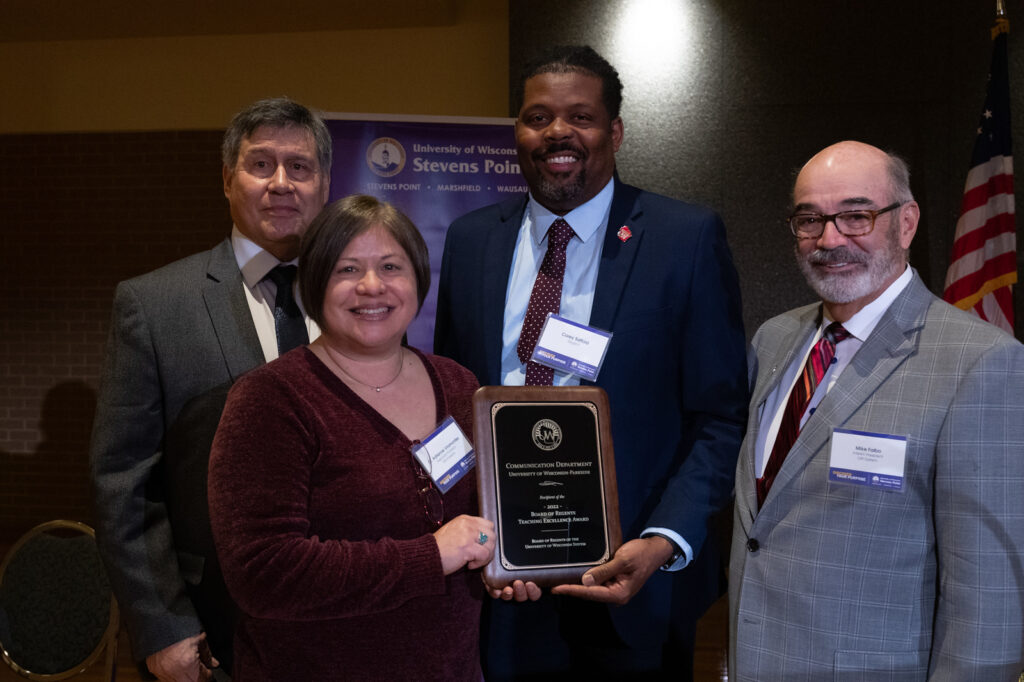 Photo of Dr. Adrienne Viramontes, chair of UW-Parkside’s Communication Department, accepting award on department's behalf; pictured with (from left) Regent President Edmund Manydeeds III, Regent Corey Saffold, and UW System Interim President Michael J. Falbo