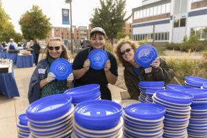 Photo of several UW-Stout staff and faculty members posing with Dining Servicebranded plates for a large cookout event.