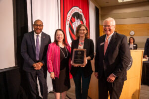 Photo of Carrie Kline, UW-Stevens Point, accepting the Board of Regents 2023 University Staff Excellence Award on October 6, 2023. Also pictured (from left) UW-Stevens Point Chancellor Thomas Gibson, Regent President Karen Walsh, and Universities of Wisconsin President Jay Rothman.