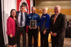 Photo of UW-Stout Dining Services Director Justin Krahn accepting the Board of Regents 2023 University Staff Excellence Award on the program's behalf. Also pictured (from left) Regent President Karen Walsh, Regent Edmund Manydeeds III, Chancellor Katherine Frank, and Universities of Wisconsin President Jay Rothman. (Photo by UW-River Falls)