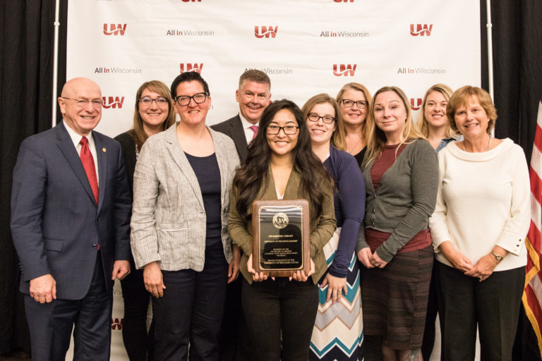 Photo of the UW System Board of Regents 2019 Academic Staff Excellence Award in the Program category being awarded to the UW-Parkside Library. (from left) Ray Cross, UW System President; Laura Briskie, Research Help and Instruction Librarian; Anna Stadick, Library Director; Regent Drew Petersen; Xou Lee Va Vang, Research Help and Instruction Librarian; Paige Barreto, Outreach and Marketing Librarian; Dina Kaye, Head of Library Collections; Melissa Olson, Head of Archives; Rebecca Robbennolt, Archivist and Records Manager; and Regent Janice Mueller (not pictured) Heather Spencer, Access Service Technology Coordinator; Liz Antaramian, Library and Archives Assistant; Dave Gehring, Access Services Manager; Jay Dougherty, Head of Library Systems; Brian Dorband, Acquisitions Supervisor; Jennie Callas, Head of Reference and Instruction; Becky Tolejano, Library Technology Support; Shauna Edson, Instructional Design Librarian; and Jean Hrpcek, Administrative Assistant