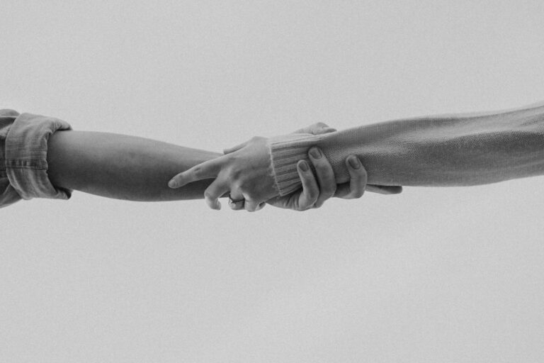 This picture depicts two people holding arms in support of each other.