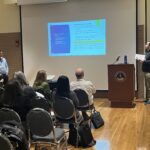 UW-Eau Claire presenting  to participants seated in chairs in a breakout session at UW System Navigate and Advising Workshop March 2023 at UW-Stevens Point