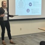 Karen Drees of UW-Platteville is standing next to a projected PowerPoint slide and gesturing during a breakout session on differentiated care at the UW System Navigate and Advising Workshop March 9, 2023, at UW-Stevens Point