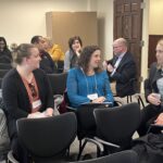 About 10 people are seated in rows and talking in groups of 3 to 4 during a breakout session at the UW System Navigate and Advising Workshop March 9, 2023, at UW-Stevens Point