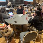 Several people seated at a round table with Marie Smith of UW-Parkside gesturing to her computer screen during the Major and Career Exploration discussion session at the UW System Navigate and Advising Workshop March 9, 2023, at UW-Stevens Point