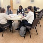 5 people seated at round table including Paige Hammond of EAB speaking at the UW System Navigate and Advising Workshop March 9, 2023, at UW-Stevens Point