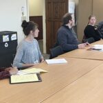 5 UW colleagues seated on one side of a boardroom table including Angela Kellogg of UW System Administration taking notes at the UW System Navigate and Advising Workshop March 9, 2023, at UW-Stevens Point