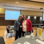 Sandy Kallio of UW System Administration and Laura Kite of UW Extended Campus standing next to hear other at the UW System Navigate and Advising Workshop March 9, 2023, at UW-Stevens Point