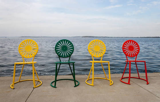 4 memorial union chairs (in order yellow, green, yellow, and orange) in front of Lake Mendota